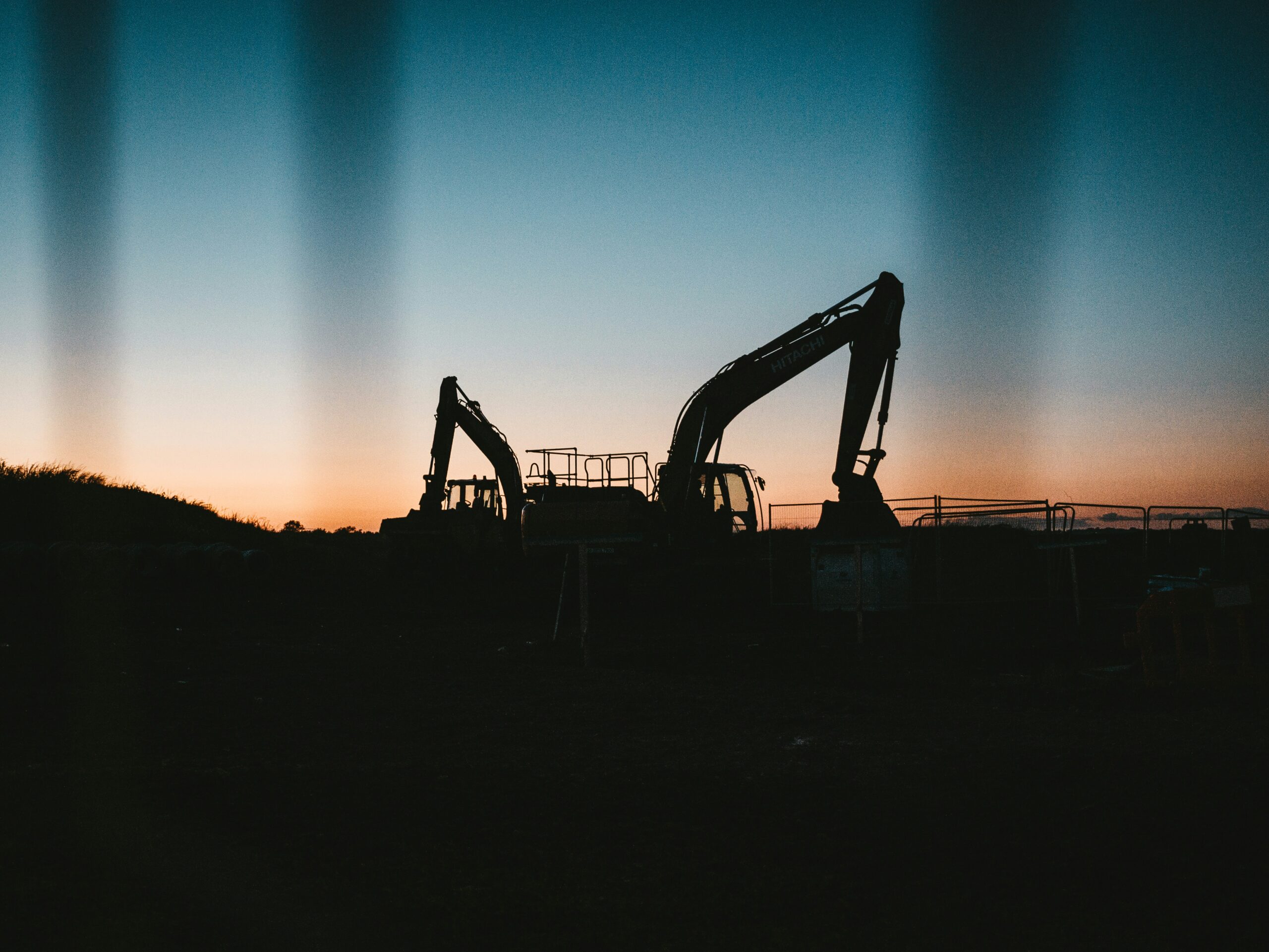 an excavator is silhouetted against a sunset